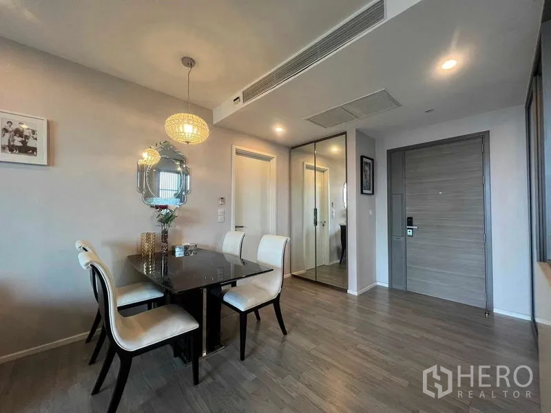 Condominium for rent in Khlong Toei, Bangkok - Dining nook with four chairs, pendant light and mirrored decor near the entry.