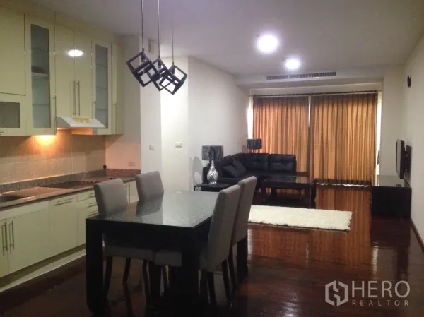 公寓 出租在Watthana, Bangkok - 开放式客餐厅，带整体厨房、几何吊灯和黑色皮沙发。