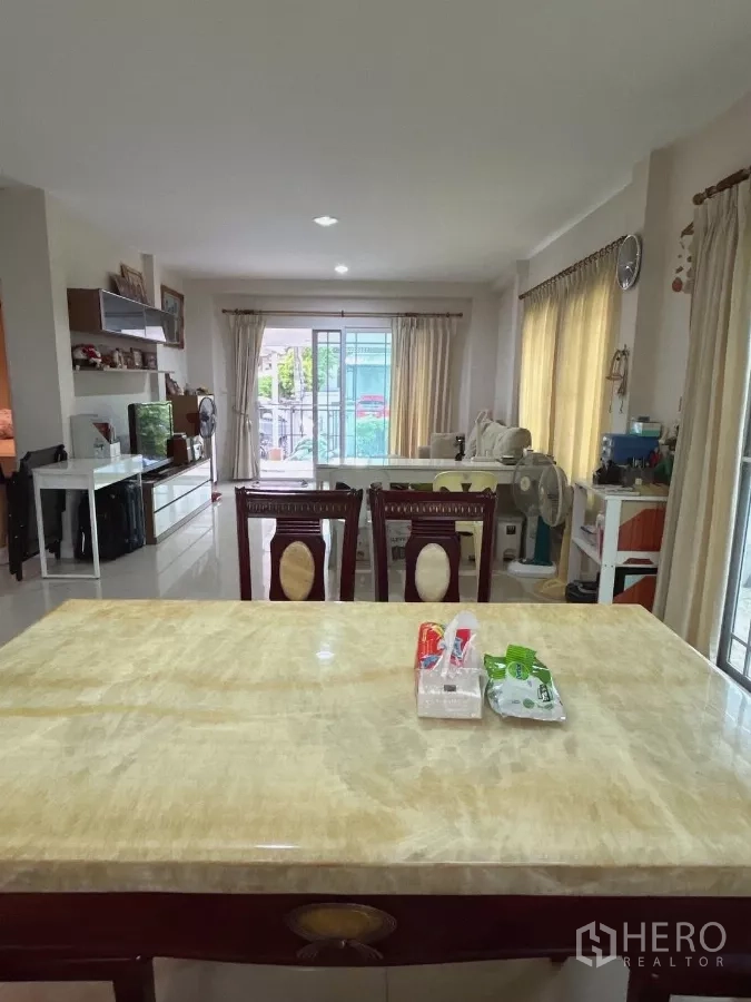 Detached House for sale in Bang Kapi, Bangkok - Dining zone facing the living area with TV unit and sliding doors to the patio.