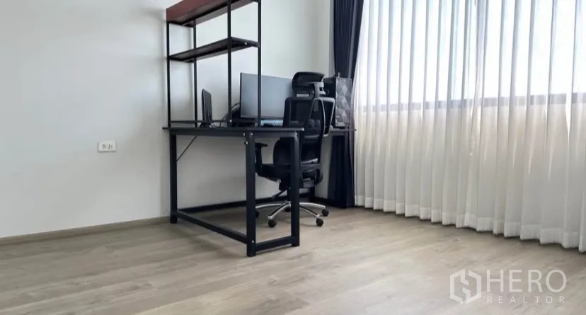 Detached House for rent or sale in Lat Krabang, Bangkok - Bright home office with desk, chair and floor‑to‑ceiling sheer curtains