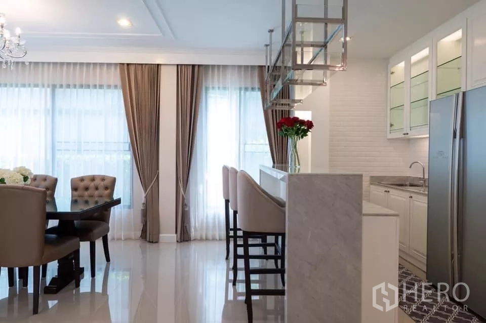 Detached House for rent in Prawet, Bangkok - Light kitchen with breakfast bar, high stools, glass cabinets and double-door fridge.