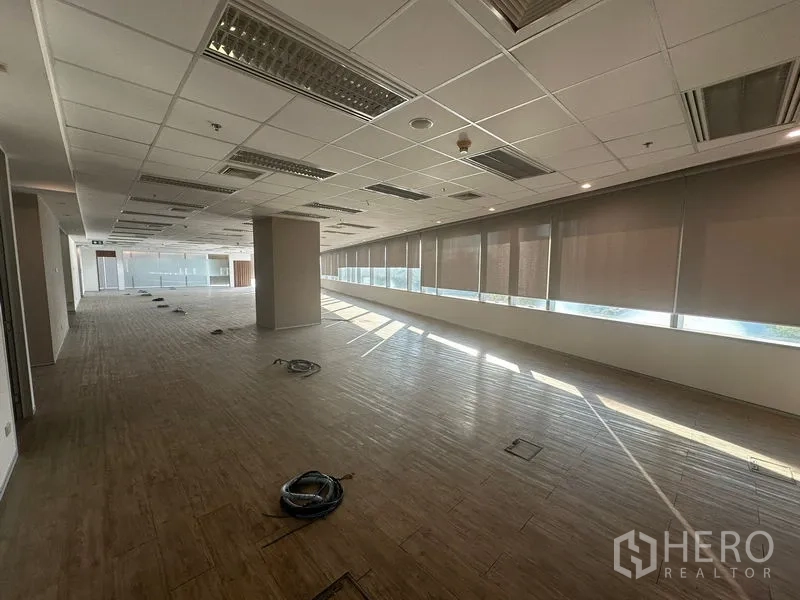 Office Space for rent in Khlong Toei, Bangkok - Long open workspace with continuous windows, blinds, and raised floor boxes.