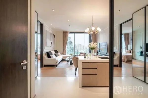 Condominium for rent or sale in Khlong Toei, Bangkok - Entry corridor to open-plan kitchen and living area with chandelier and balcony view.