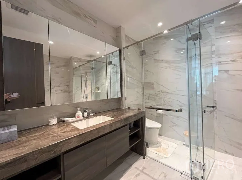 Condominium for rent or sale in Sathon, Bangkok - Luxurious bathroom with long stone vanity, large mirrors and glass shower enclosure.