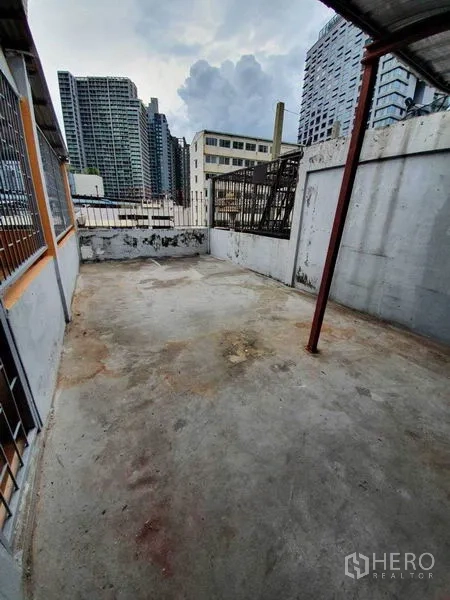 Shophouse for rent in Watthana, Bangkok - Open rooftop terrace with concrete floor and city skyline views.