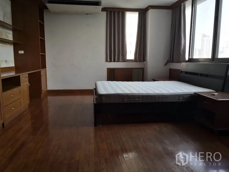 公寓 出租在Khlong Toei, Bangkok - 转角卧室，木地板，内置书桌与置物架，大窗配遮光窗帘，可见城市景观