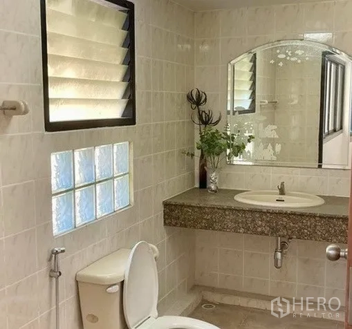 Home Office for rent in Khlong Toei, Bangkok - Tiled bathroom featuring a large mirror, glass-block window and countertop basin.