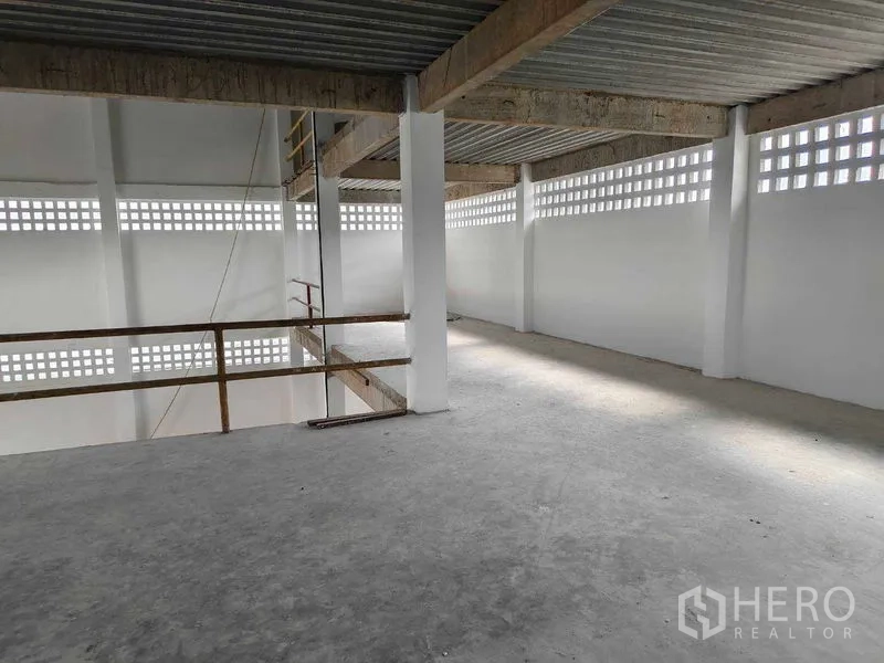 Warehouse for rent in Phra Khanong, Bangkok - Upper mezzanine level with concrete floor, safety railing, and ventilated block walls.