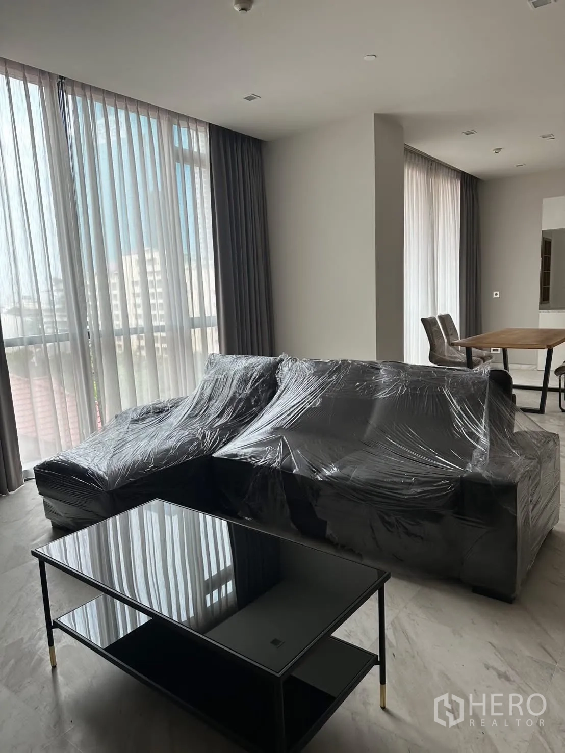 คอนโด for rent or sale in Watthana, Bangkok - โถงรับแขกแบบโอเพ่นเพลนมีโซฟาเข้ามุมและผ้าม่านโปร่ง.