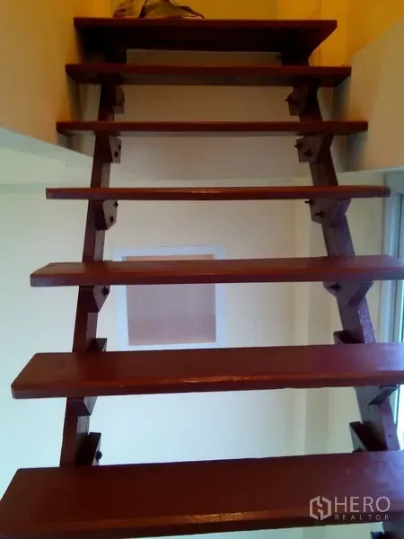 Shophouse for rent in Phra Khanong, Bangkok - Open-riser wooden staircase leading to a mezzanine inside the shophouse.