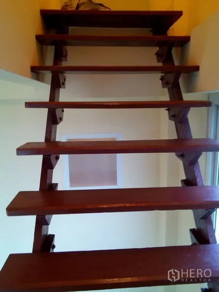 Shophouse for rent in Phra Khanong, Bangkok - Open-riser wooden staircase leading to a mezzanine inside the shophouse.