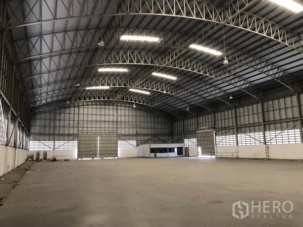 货栈 出租在Pathum Thani - 宽阔存储空间，挑高屋顶、金属覆墙，角落设办公室。