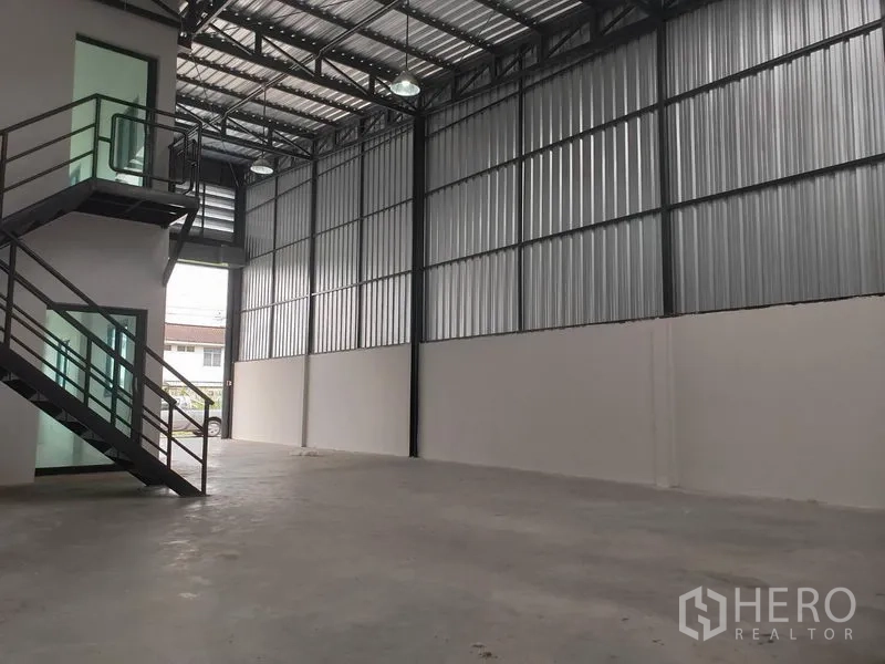 Warehouse for rent or sale in Lam Luk Ka, Pathum Thani - Open warehouse floor with ribbed metal walls, black steel columns and skylights for natural light.