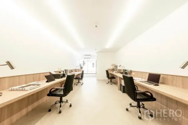 办公空间 出租在Khlong Toei, Bangkok - 明亮的开放式办公室，长条木质工位配台灯与人体工学椅，尽头为窗户，位于Phra Khanong。