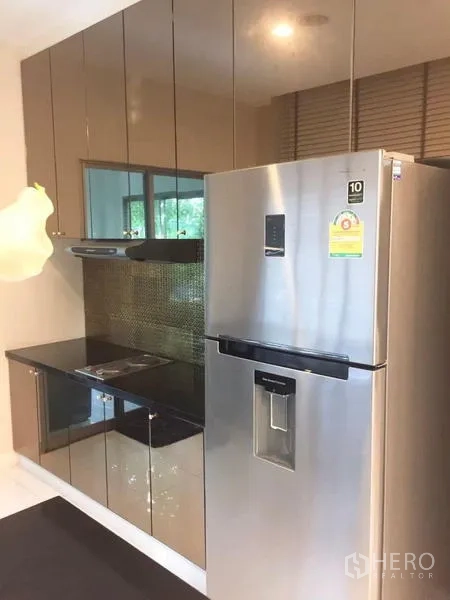 Detached House for sale in Lat Krabang, Bangkok - Tall stainless refrigerator beside glossy cabinetry and electric cooktop.