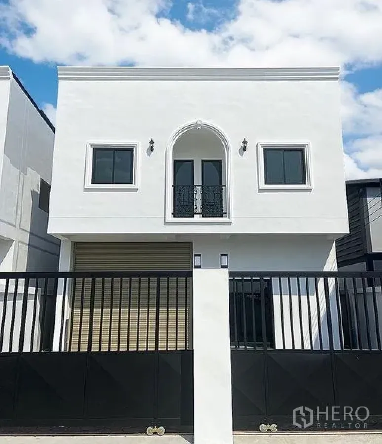 Warehouse for rent in Mueang Pathum Thani, Pathum Thani - Front elevation with black sliding gate and white facade showcasing the arched balcony.