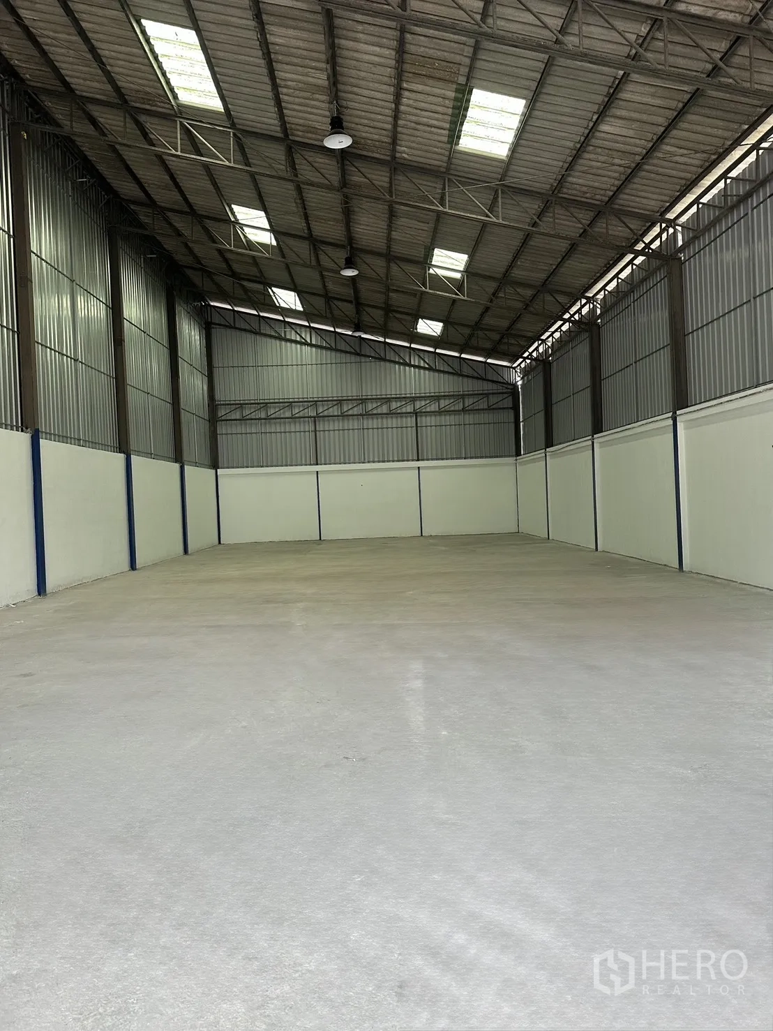Warehouse for rent in Mueang Samut Prakan, Samut Prakan - Open-plan warehouse interior with high gable roof, skylights, and concrete floor.