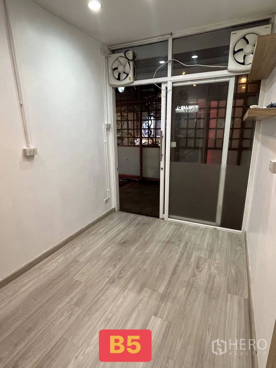 Retail Space for rent in Watthana, Bangkok - Narrow shop space with recessed lighting, laminate flooring, and a glass entrance fitted with twin ventilation fans.