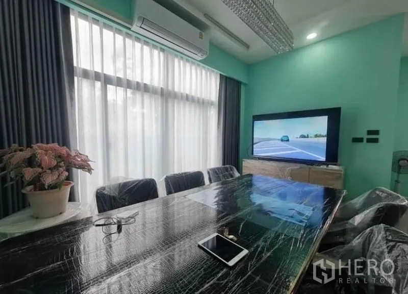 Detached House for sale in Sai Mai, Bangkok - Close-up of the dining space with a long table, TV console, and split-type air conditioner.