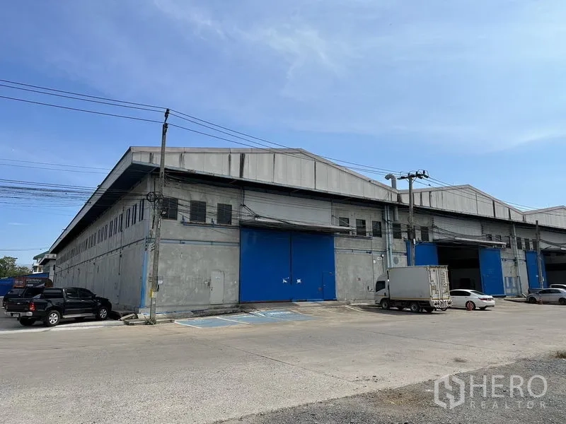 คลังสินค้า ให้เช่าในBang Phli, Samut Prakan - ด้านหน้าคลังสินค้าพร้อมประตูม้วนสีน้ำเงินขนาดใหญ่ รองรับรถบรรทุกเข้าออกสะดวก