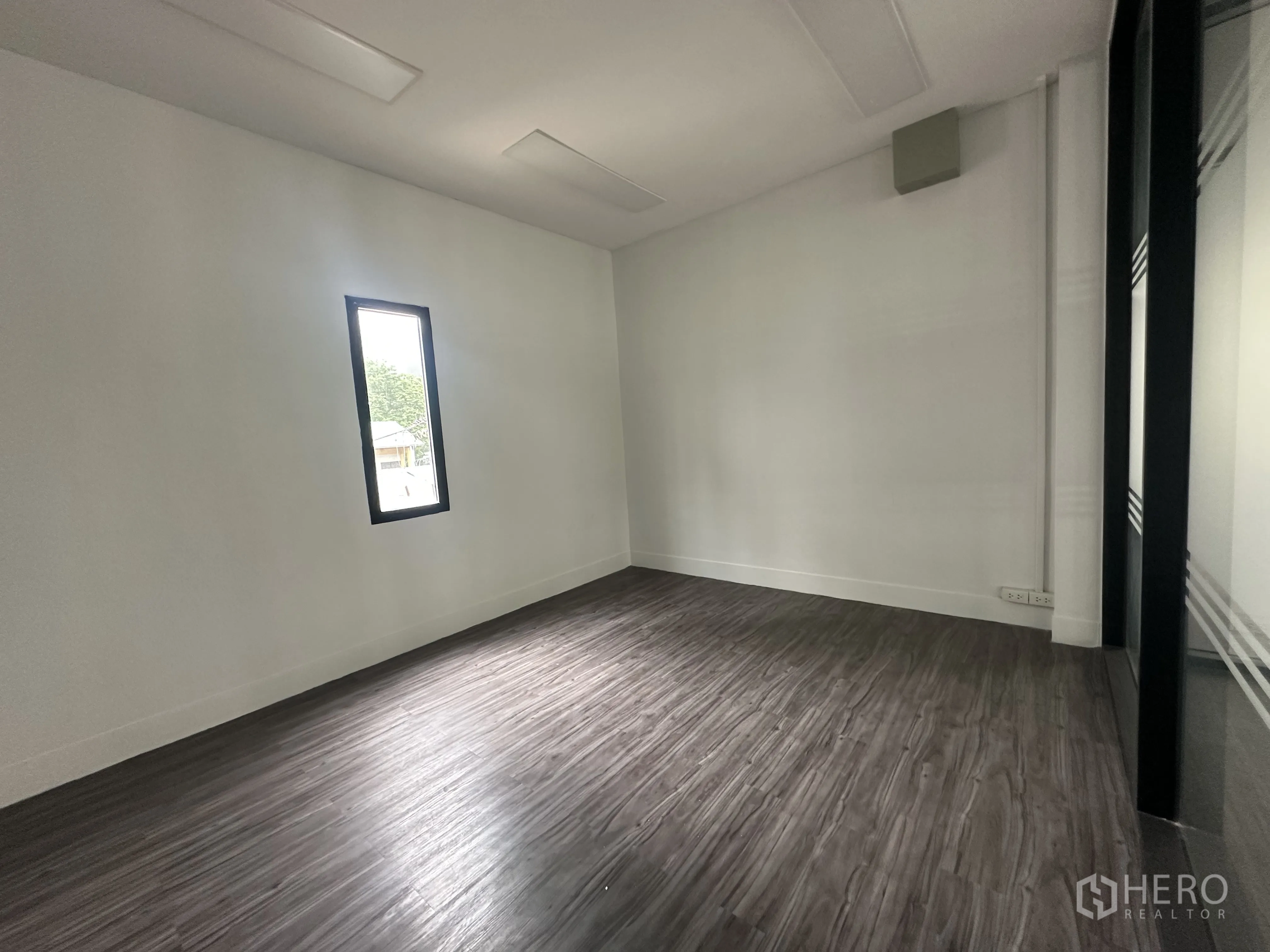 Retail Space for rent in Bang Rak, Bangkok - Private room with narrow window, white walls and dark wood-look flooring.