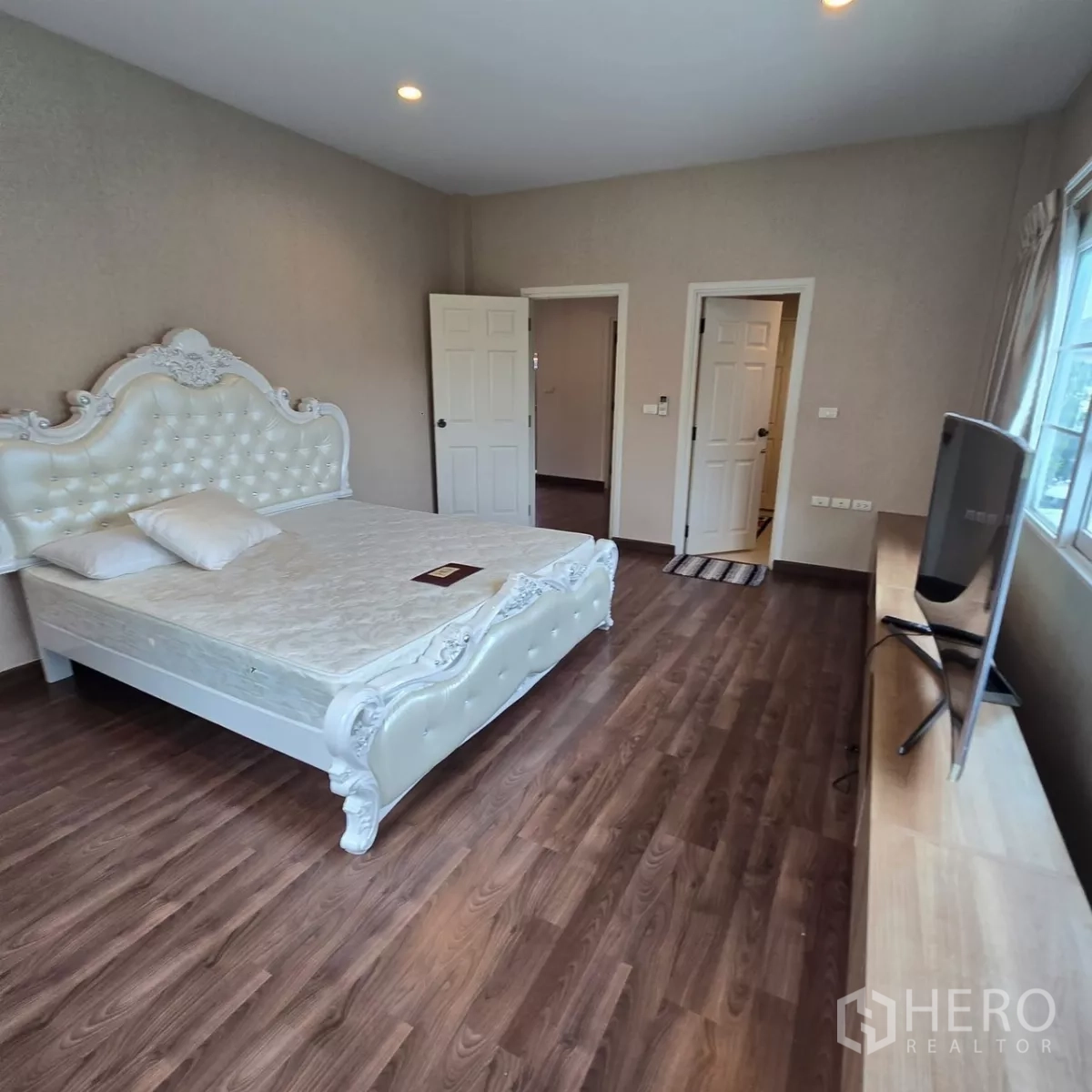 Detached House for rent in Mueang Pathum Thani, Pathum Thani - Second bedroom with ornate white bedframe, wood floors and TV shelf.