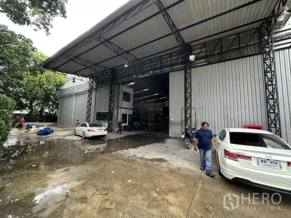 Factory for rent in Bang Bua Thong, Nonthaburi - Covered loading bay with a tall steel canopy and a large shutter entrance.