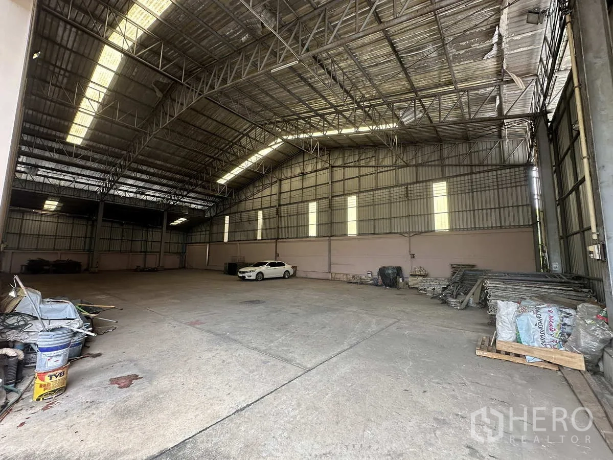Factory for rent in Pathum Thani - Spacious warehouse interior with a high steel-truss roof, skylights and clear-span concrete floor.