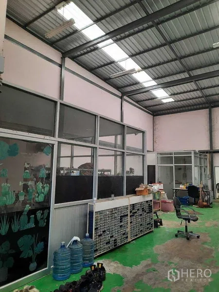 Warehouse for sale in Samut Prakan - Partitioned office windows inside the warehouse under fluorescent lighting.