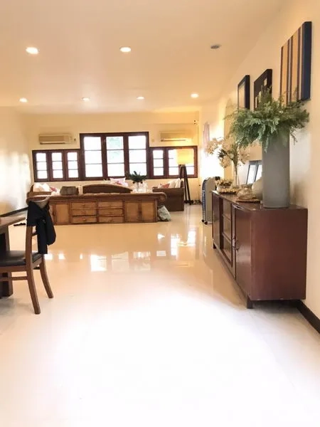 Detached House for rent in Phra Khanong, Bangkok - Long open-plan lounge with a wall of windows, built-in cabinets, and glossy tile floors.