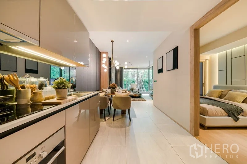 Condominium for rent in Watthana, Bangkok - Sleek galley kitchen opening to dining and living spaces with a bedroom suite to the right.