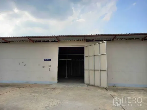 คลังสินค้า ให้เช่าในPathum Thani - ด้านหน้าโกดังพร้อมประตูเหล็กบานใหญ่และลานคอนกรีต เมืองปทุมธานี