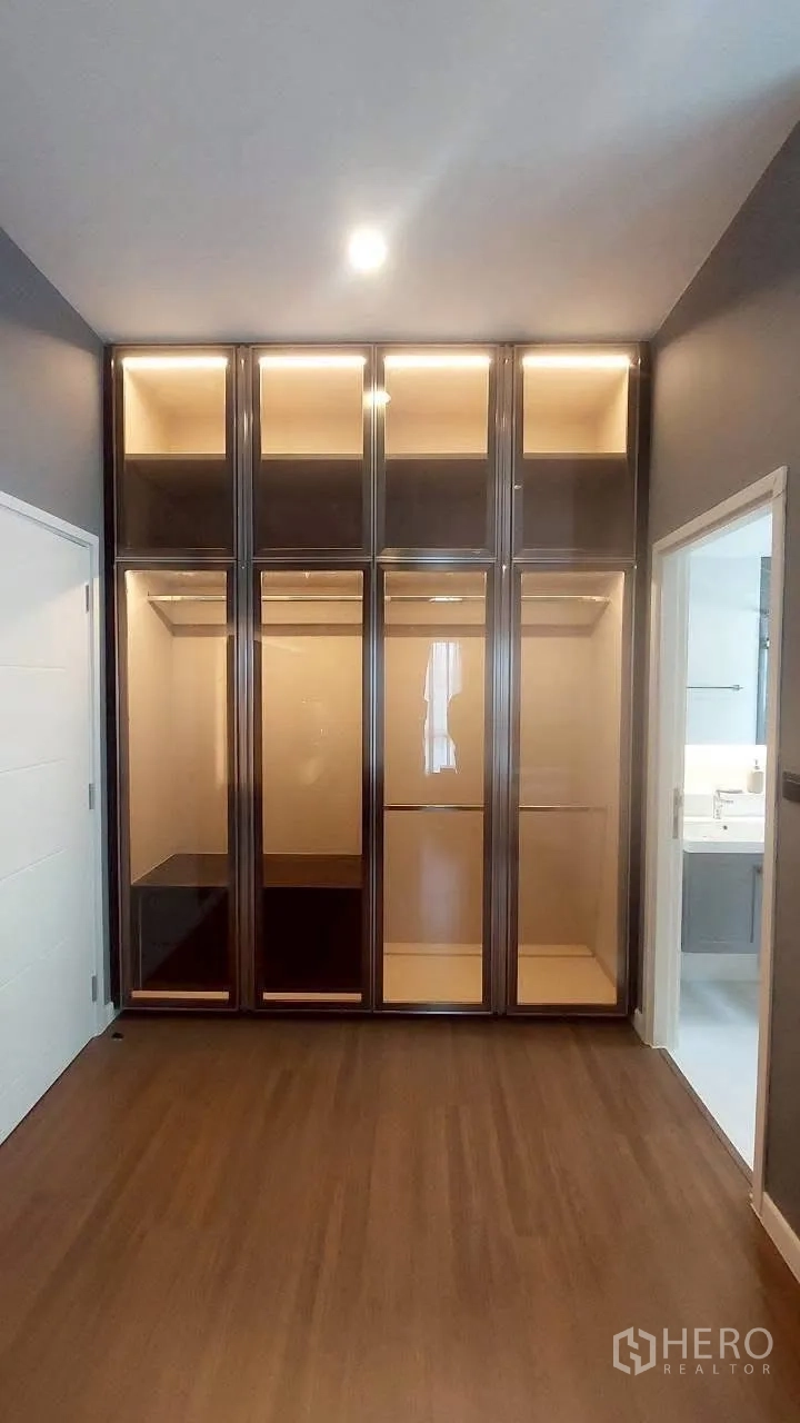 Detached House for rent in Bang Phli, Samut Prakan - Tall built-in glass wardrobes in a bedroom with wood floors.