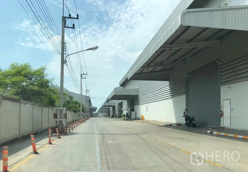 Factory for rent in Wang Noi, Phra Nakhon Si Ayutthaya - Long industrial estate street with multiple loading docks and roll-up doors along both sides.