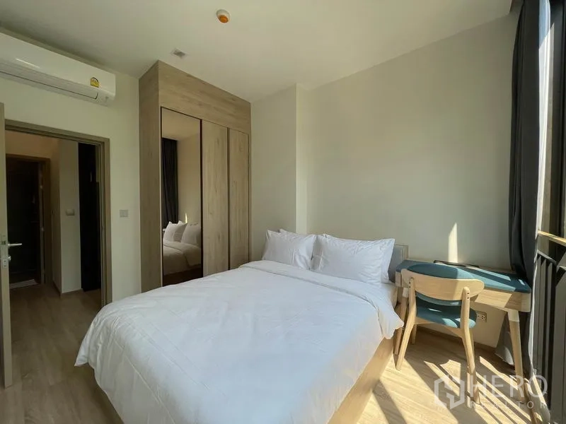 Condominium for sale in Watthana, Bangkok - Second bedroom featuring a mirrored wardrobe and a study desk by the window.