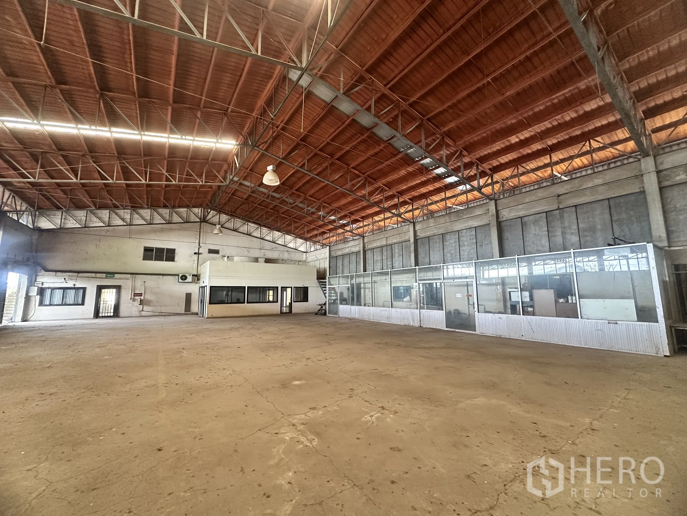 Factory for sale in Sai Noi, Nonthaburi - Spacious factory floor with high steel truss roof, concrete slab, and glass-partitioned offices.