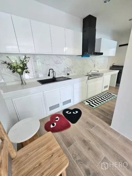 Townhouse for rent in Saphan Sung, Bangkok - Sleek white kitchen with marble backsplash, black sink and range hood.
