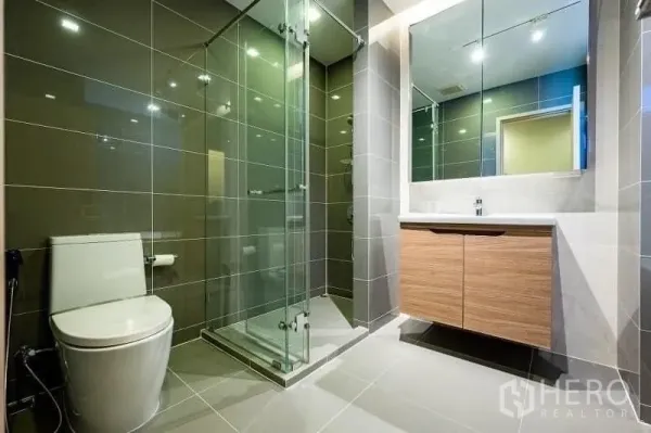 Condominium for sale - Contemporary bathroom with glass-enclosed shower, large mirror and gray tiles.