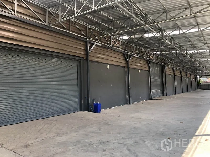 Factory for rent or sale in Bang Bo, Samut Prakan - Row of roller shutter loading doors along a covered platform.