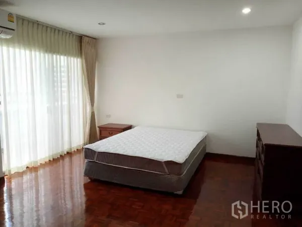 公寓 出租在Watthana, Bangkok - 采光充足的卧室，双人床、落地窗帘与通往阳台的门