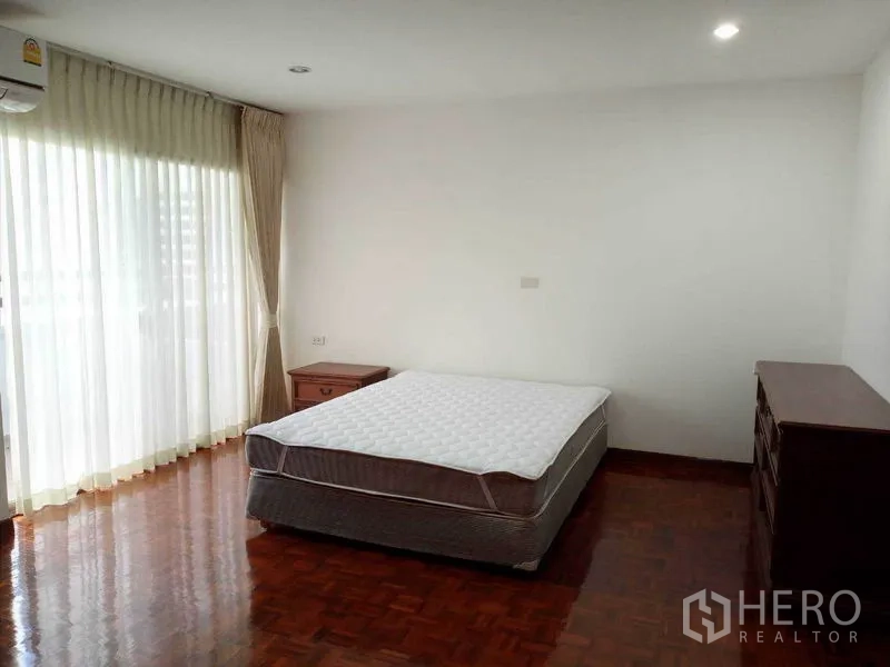 公寓 出租在Watthana, Bangkok - 采光充足的卧室，双人床、落地窗帘与通往阳台的门
