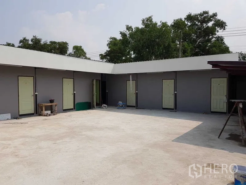 Warehouse for sale in Lam Luk Ka, Pathum Thani - Paved courtyard with a row of rooms and light-green doors, suitable for worker accommodation.