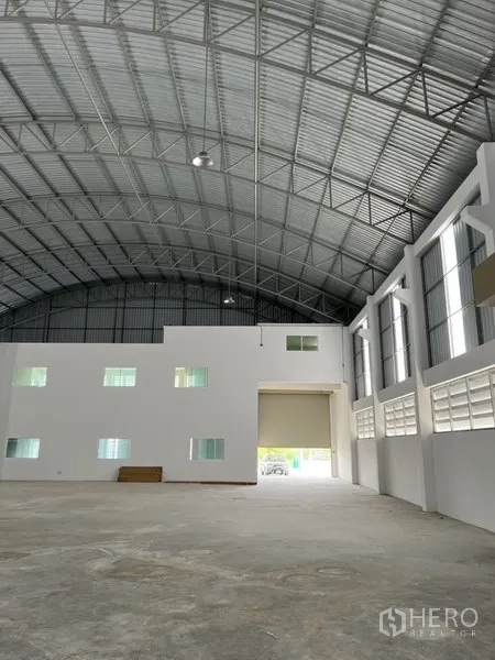 工厂 出租或出售在Bang Bo, Samut Prakan - 宽敞生产大厅，高挑拱形钢屋顶，白色办公室区与大型卷帘门。