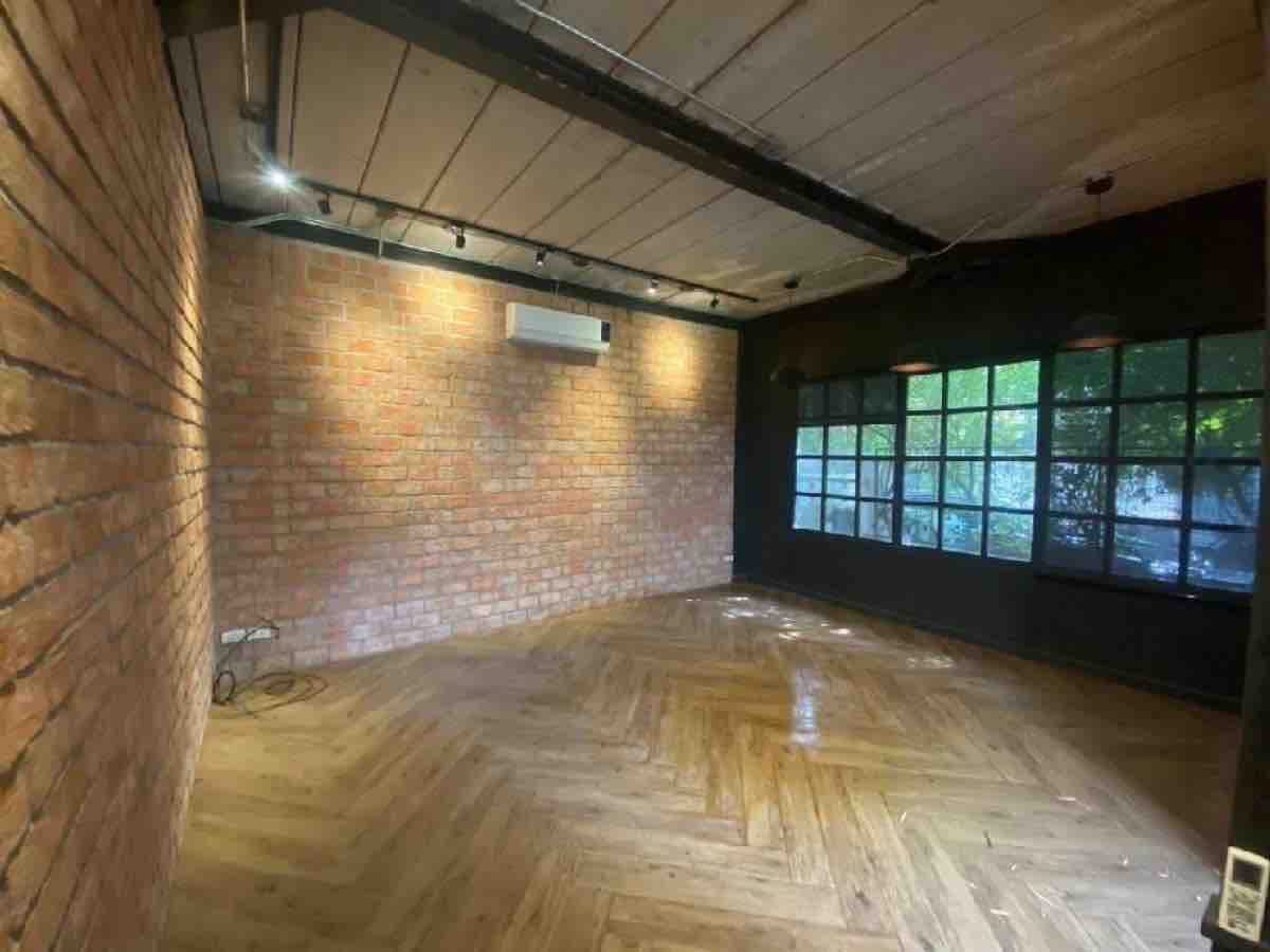 Retail Space for rent in Watthana, Bangkok - Loft-style retail room with exposed brick, herringbone wood flooring, track lights and black-framed windows.