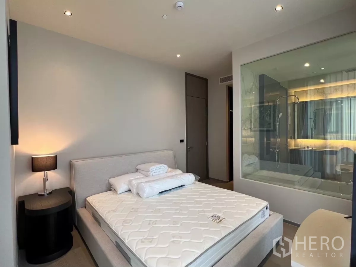คอนโด ให้เช่าในWatthana, Bangkok - ห้องนอนมาสเตอร์พร้อมเตียงคิง โต๊ะข้างเตียง และช่องหน้าต่างสู่ห้องน้ำ
