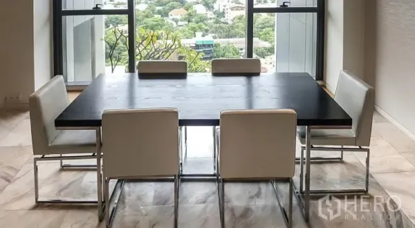 公寓 出租或出售在Sathon, Bangkok - 现代餐区，深色餐桌与六把白色椅子，落地窗外是城市绿景。