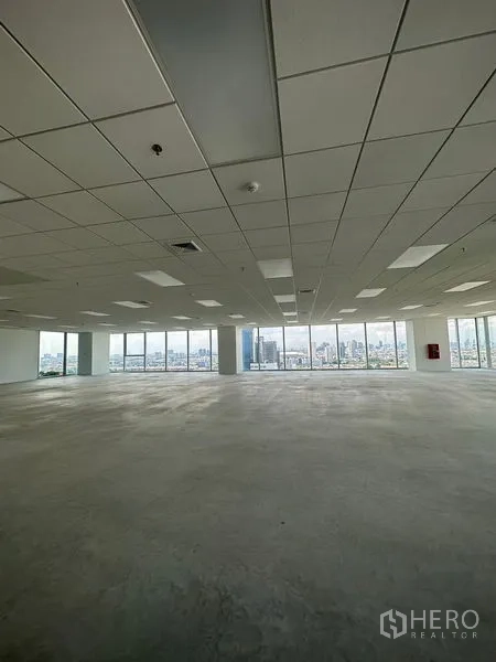 Office Space for rent in Bang Na, Bangkok - Large unfurnished office area featuring suspended ceiling panels, concrete floor, and expansive windows overlooking the city.
