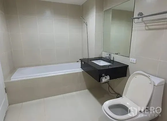 คอนโด ให้เช่าในHuai Khwang, Bangkok - ห้องน้ำพร้อมอ่างอาบน้ำ โถสุขภัณฑ์ กระจกบานใหญ่ และอ่างล้างหน้าแขวนผนัง