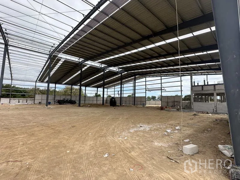 货栈 出租或出售在Nikhom Phatthana, Rayong - 宽敞仓库内部，一侧屋面板已安装，留出大型装卸区域。
