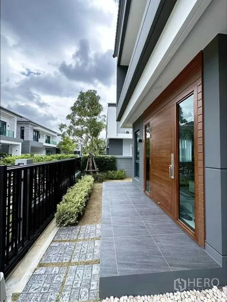 独立式住宅 出租或出售在Bang Phli, Samut Prakan - 侧院露台与花园步道，临围栏与木门。